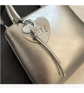 Detail of silver textured leather bucket bag with heart tag and metallic buckle