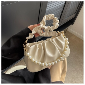Close-up of cream pleated cloud bag featuring large pearl chain and soft PU texture