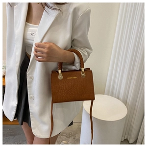 Brown crocodile pattern crossbody bag with a unique woven handle and gold hardware