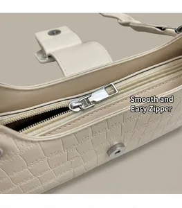 Close-up of smooth silver zipper and magnetic buckle on cream embossed shoulder bag