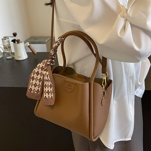 Vista dettagliata di una borsa a secchiello in pelle marrone con elegante foulard di seta
