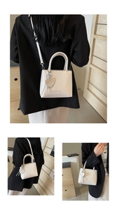 Detail view of cream white bucket bag with heart pendant and detachable shoulder strap