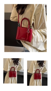Detail of red glossy leather bucket bag with heart pendant and detachable shoulder strap