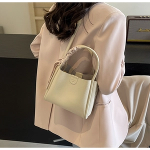 Dettaglio borsa a secchiello in pelle crema con manico avvolto da foulard rosa