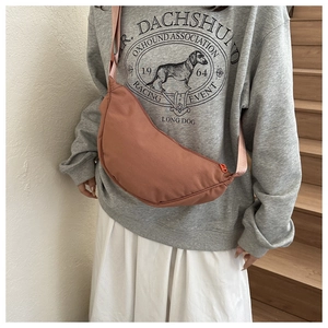 Detail view of brick orange crescent crossbody bag with adjustable nylon strap and fabric texture