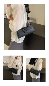Detail of black crocodile pattern baguette bag with braided shoulder strap and buckle