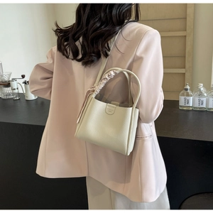 Elegante borsa a secchiello in pelle crema con foulard floreale in un contesto di stile
