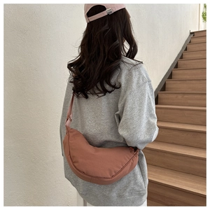 Detail of a minimalist dark pink crescent crossbody bag with adjustable nylon strap