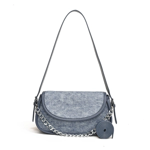 Blue denim underarm bag with silver chain strap and leather piping on white background