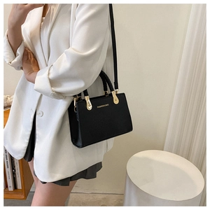 Detail of black faux leather bag featuring woven handle and gold fashion and bag logo
