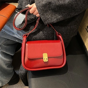 Vintage red crossbody flap bag with gold buckle worn by a woman in a grey wool coat
