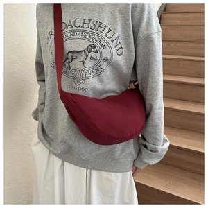 Detail of burgundy crescent crossbody bag with adjustable wide strap on a model