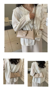 Detail of beige crocodile embossed baguette bag with metal chain and buckle strap