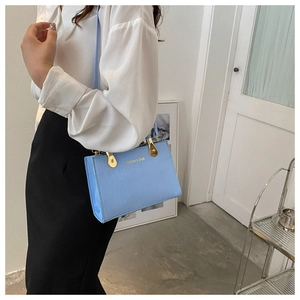 Detail of light blue handbag with crocodile texture and gold FASHION & BAG lettering