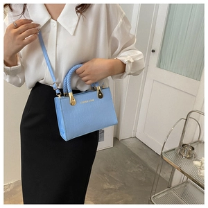 Detail of light blue faux crocodile bag with woven handle and gold hardware