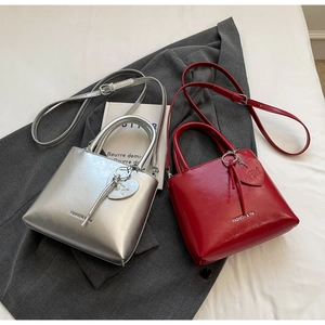 Macro detail of silver and red trapezoid bags with heart charms on grey blazer
