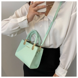 Detail of light green satchel with woven handle and gold metal hardware accents