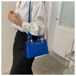 Blue textured leather crossbody bag detail with gold hardware and fashion logo