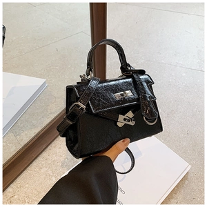 Detail of glossy black wrinkled leather texture and silver metal twist lock on Kelly bag
