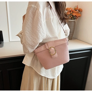 Detailed side view of pink woven bucket bag with leather strap and golden hardware buckle