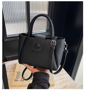 Detail of black lychee grain leather handbag with silver hardware and detachable strap