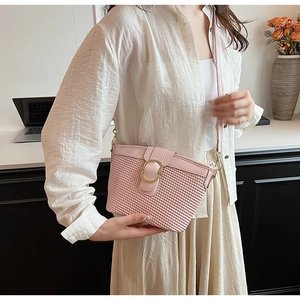 Detail of pink woven leather shoulder bag with a gold buckle in a modern office setting