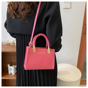 Detail view of pink crocodile embossed leather bag with gold hardware and woven handle