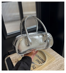 Close-up of a silver bowling bag with pleated metallic texture and cylindrical handles