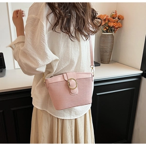 Pink woven texture crossbody bag with gold hardware shown on person for size reference