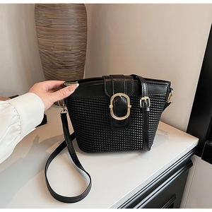 Detail of black woven texture crossbody bucket bag with elegant gold oval buckle