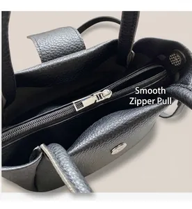 Detailed macro view of the smooth silver zipper and lychee grain leather on the black bucket bag