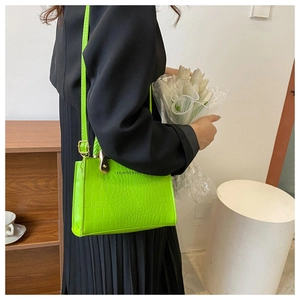 Neon green crocodile texture handbag with gold metal clasp on a minimalist background