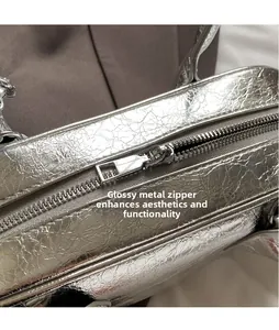 Détail de la fermeture éclair en métal argenté sur un sac bowling en similicuir froissé