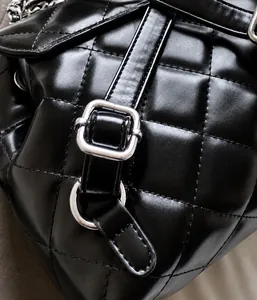 Detail der gesteppten schwarzen Lederstruktur und Schnalle am modischen Mini-Rucksack
