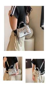 Detail of silver metallic Kelly bag showing mini handle and crossbody strap style