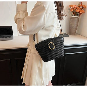 Close-up of black woven leather crossbody bag with golden metal buckle and shoulder strap