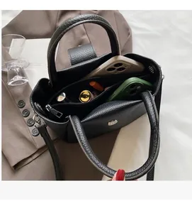 Spacious interior of black lychee leather bucket bag with phones and makeup accessories