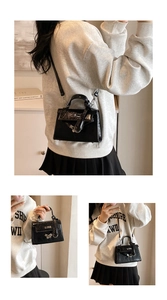 Detail of black crocodile pattern leather handbag with silver metallic turn-lock closure