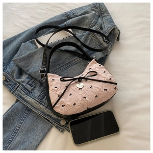 Pink pleated handbag with black bow prints and heart pendant in a lifestyle setting