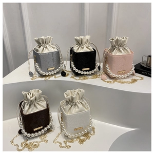 Five colored drawstring bucket bags with pearl handles and metallic chain straps on a white display