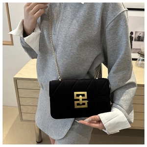 Detail of black quilted velvet crossbody bag featuring a gold geometric metal buckle