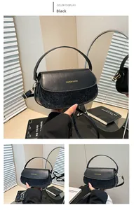 Detail of black leather saddle bag showing sequin panel, gold hardware, and top handle