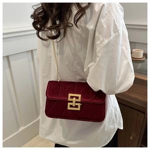 Detailed view of burgundy velvet crossbody bag with quilted pattern and gold chain strap