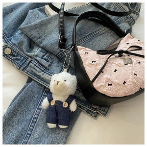 Pink pleated handbag with black bows and a cute teddy bear charm on denim jacket
