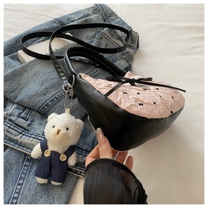 Detail of pink pleated handbag with black bows and a cute plush bear charm accessory