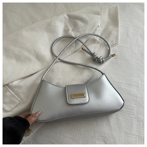 Detail of silver half-moon shoulder bag with golden metallic buckle and knotted strap