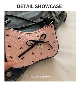Detail of pink pleated texture underarm bag with black bow and heart metal pendant