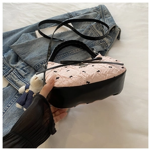 Close-up of pink and black crossbody handbag featuring bubble texture and bow decoration