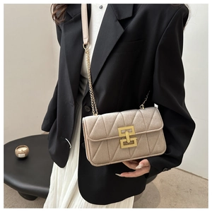 Close-up of champagne velvet quilted bag with gold chain strap on a black blazer