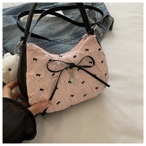Detail of pink bow pattern fabric and silver heart charm on a stylish crossbody bag
